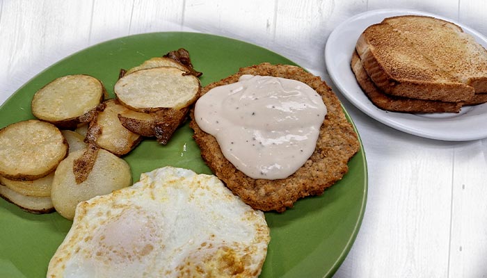 Country fried breakfast steak topped with homemade sausage gravy, served with fried eggs, potatoes and toast at Pine Cone Café in Land O' Lakes, WI